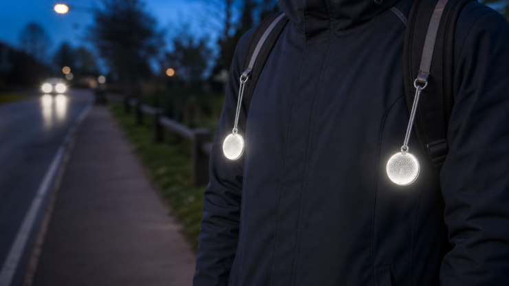 Two EN 17353 Type B1-style free-hanging reflectors worn on the left and right sides of a pedestrian torso at dusk